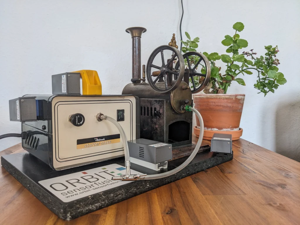 Kompressor treibt Spielzeug-Dampfmaschine an. Sensoren messen Vibration.